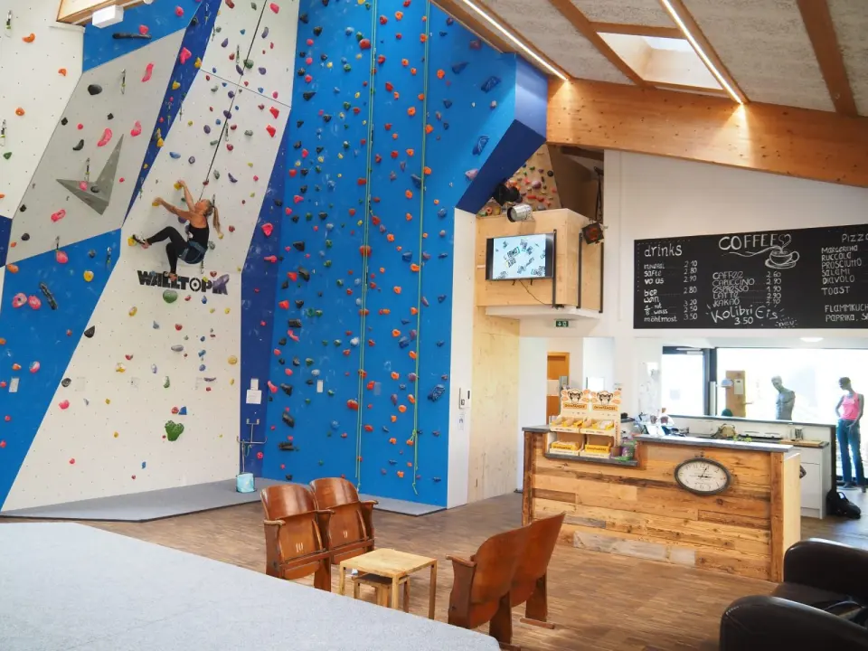 Climber on the roped wall next to the café counter and seating