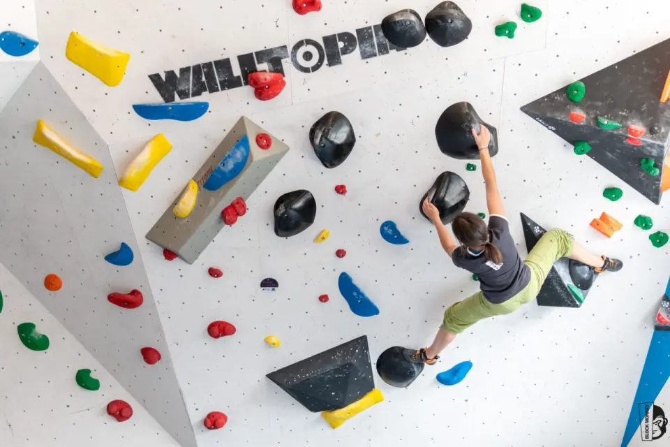 Climber on an overhanging boulder with black volumes