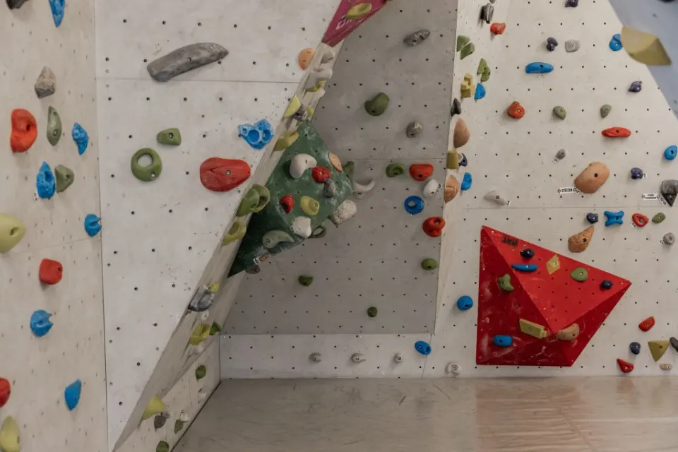 Bouldering wall with a red volume and a corner of colourful holds