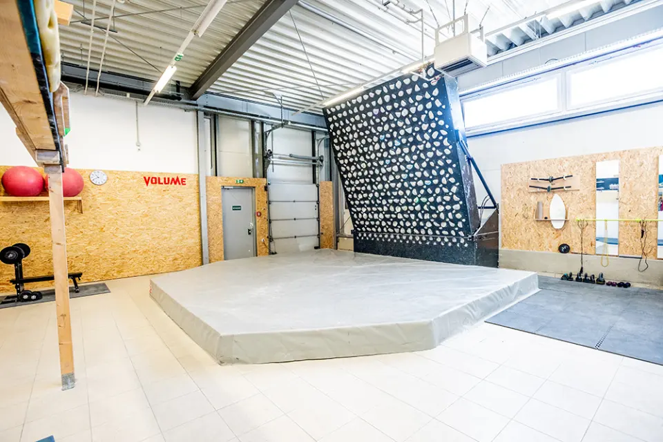 Training area with a steep LED board above a raised mat, plus weights and rigs