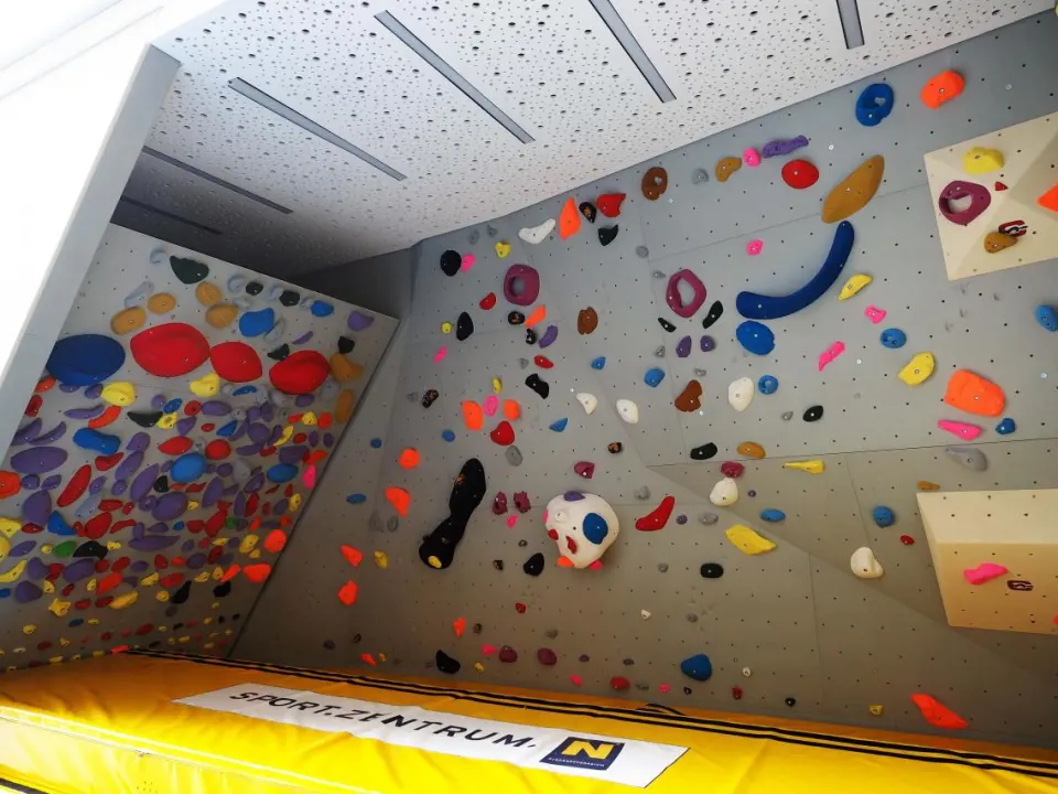 Overhanging bouldering walls above a thick yellow crash mat