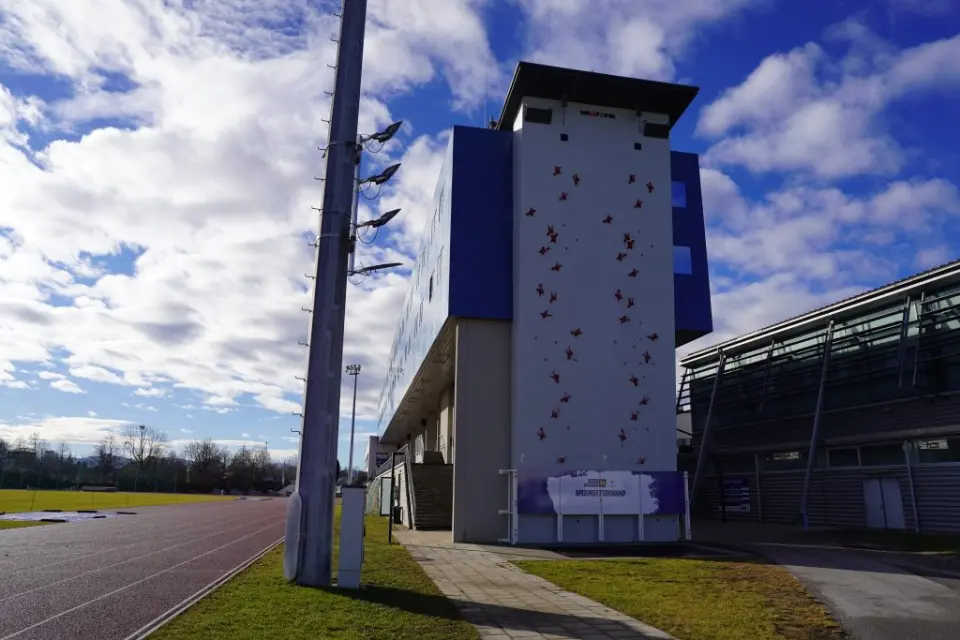 Outdoor speed climbing wall on a tower beside an athletics track