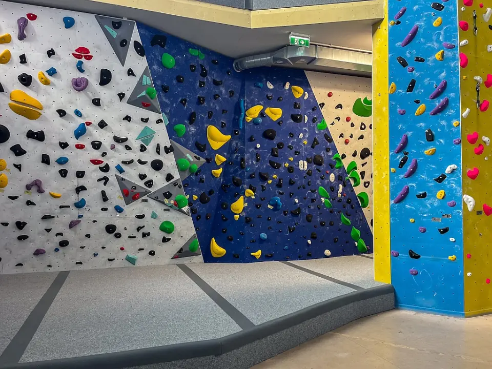 Bouldering walls in white, blue and cream above grey crash mats