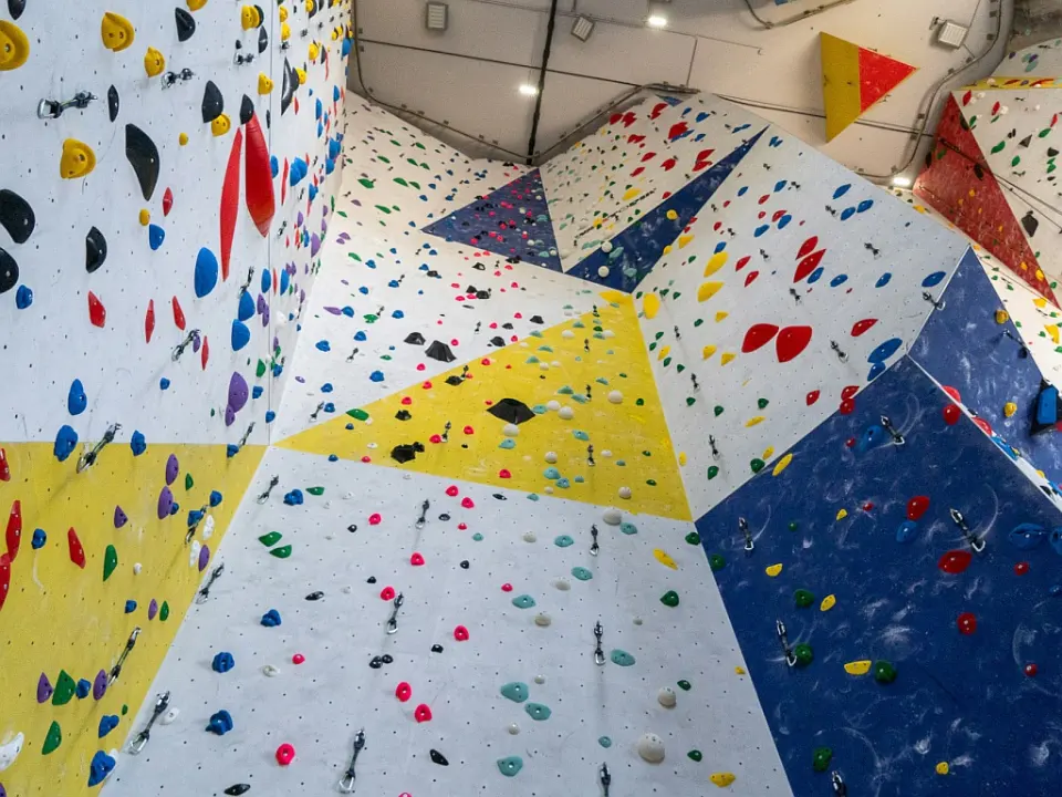 Looking up roped walls with quickdraws on white, yellow and blue panels