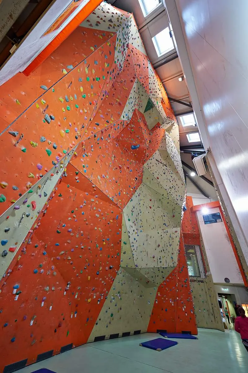 Steep orange lead wall with quickdraws rising to the roof