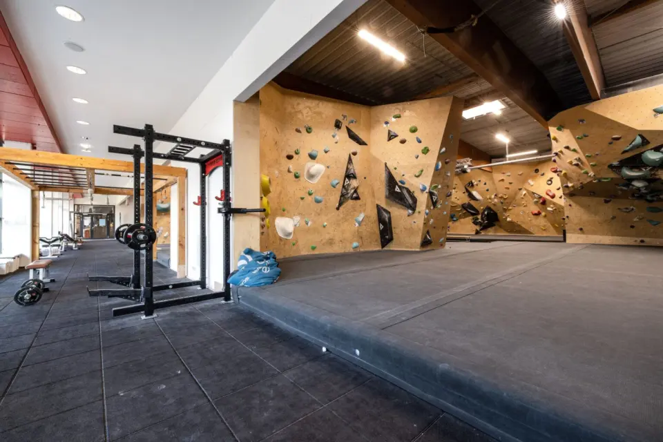 Training area with a power rack and weights beside bouldering walls
