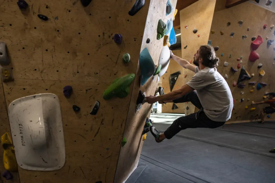Climber heel-hooking around the corner of a steep boulder