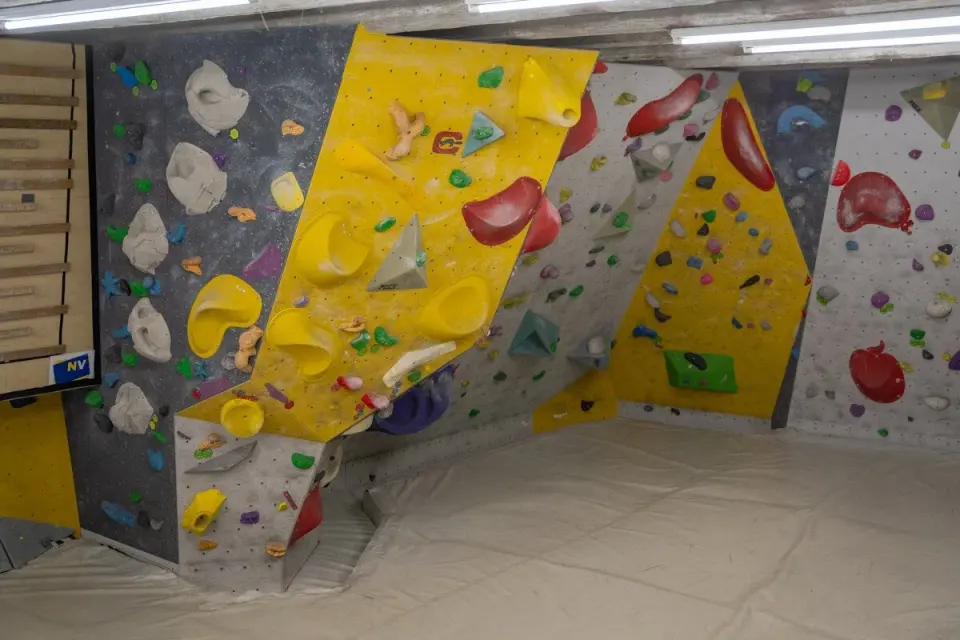 Yellow and grey bouldering walls with big volumes above white matting