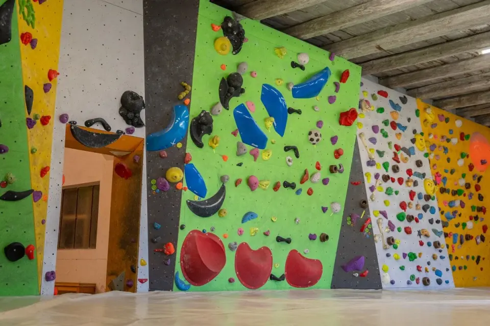 Long green, white and yellow bouldering wall under a timber ceiling
