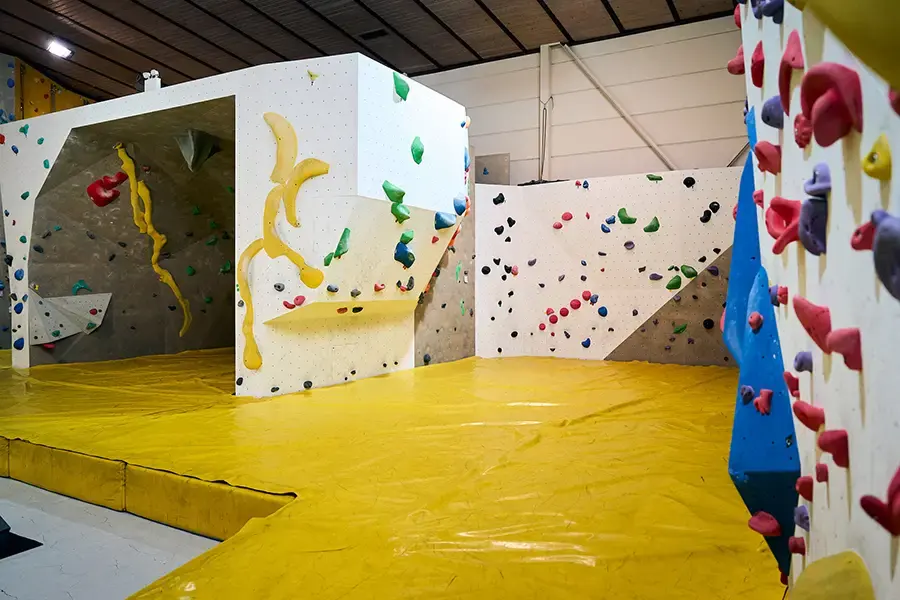 Bouldering area with white walls, a cave and yellow matting