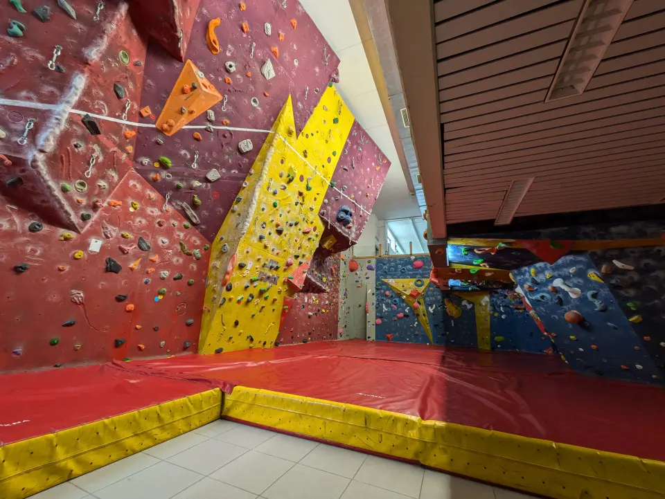 Red and yellow lead wall and a blue bouldering wall above red and yellow mats
