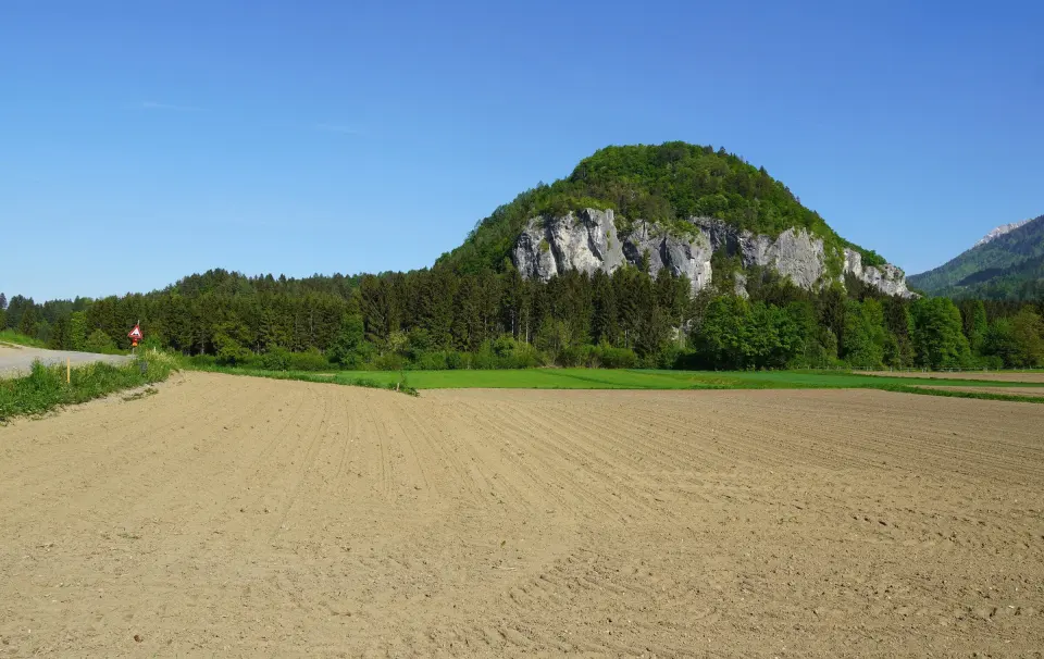 The Kanzianiberg's limestone crag rising above woods and fields near the Faaker See