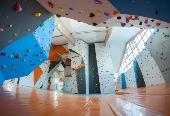 Wide view of blue, white and grey climbing walls above orange matting