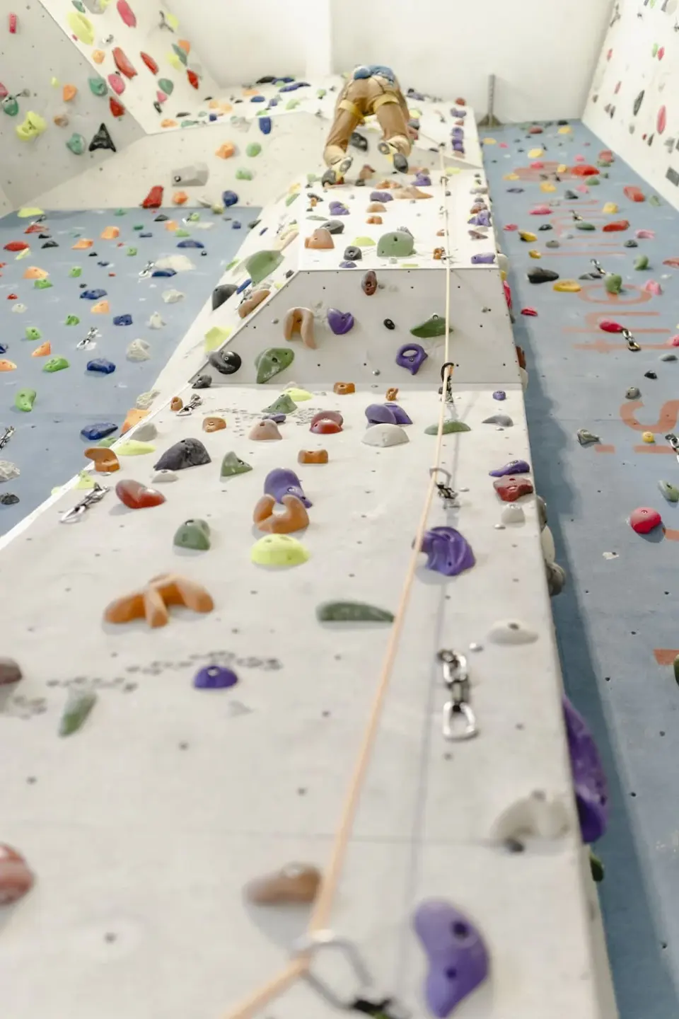 Looking up a tall climbing wall to a climber near the top