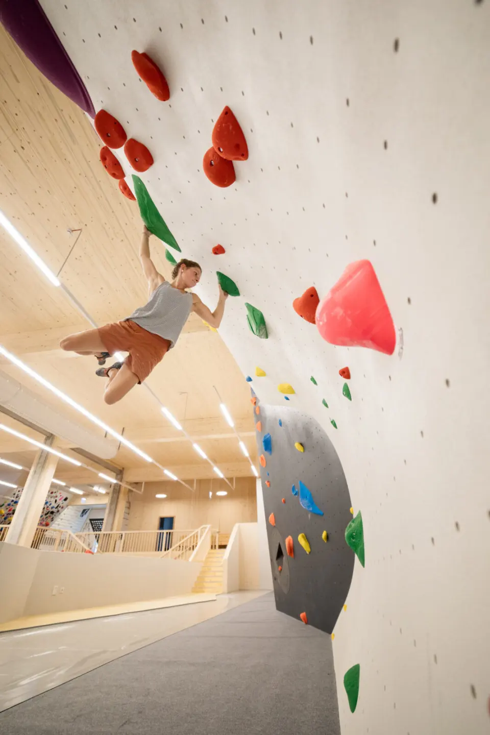 Climber reaching between red holds on an overhanging wall