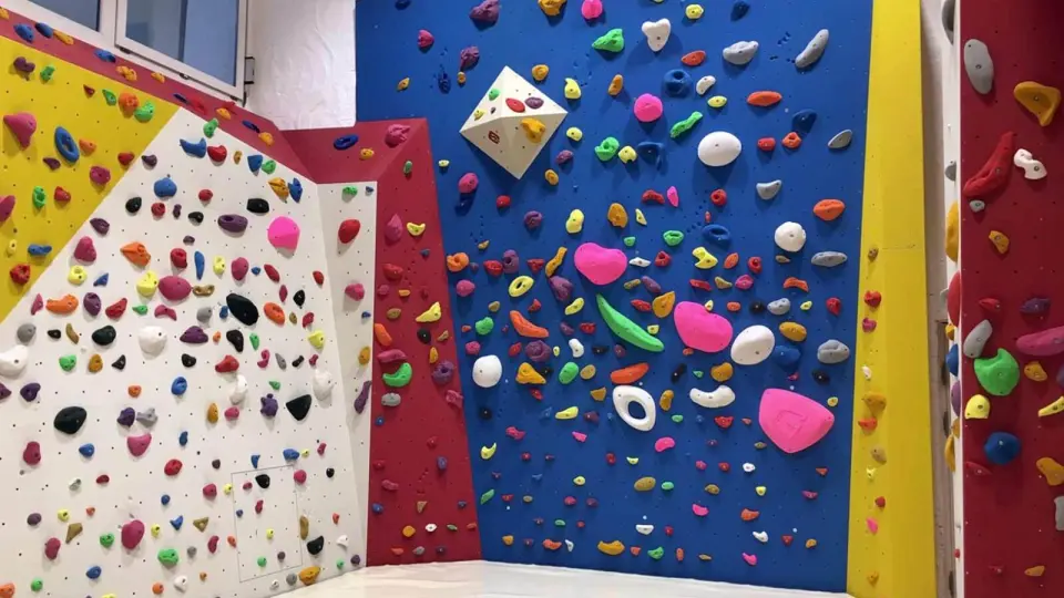 Blue, red, yellow and white bouldering walls covered in colourful holds