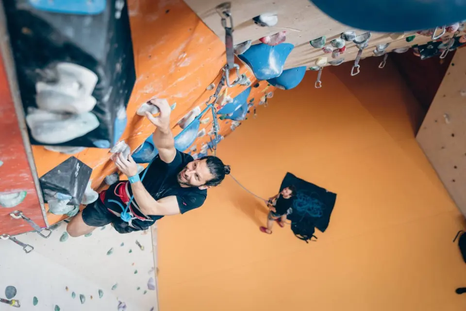 Lead climber clipping quickdraws under a steep orange overhang