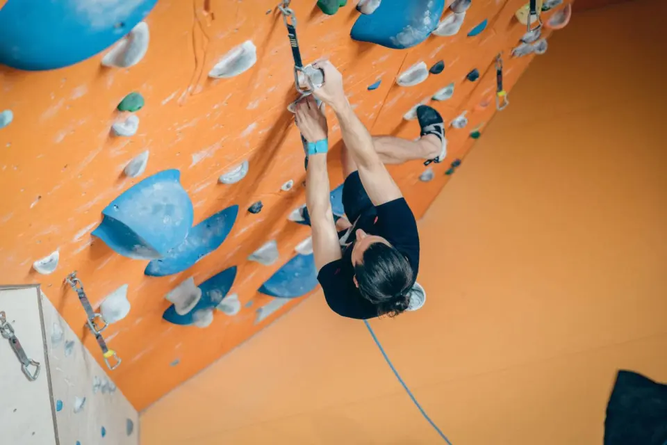 Climber seen from above on an orange overhang with large blue volumes