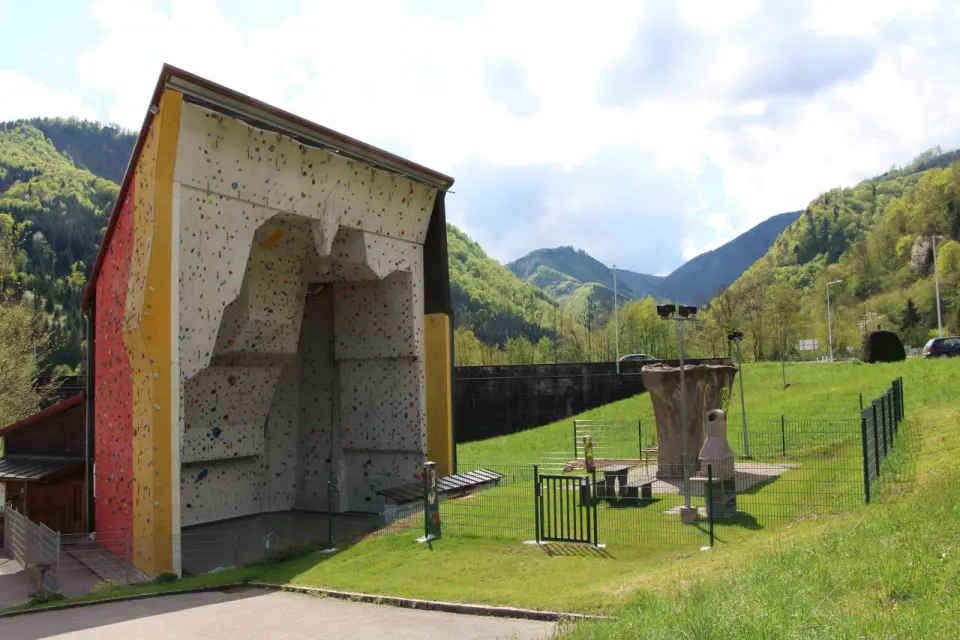 Roofed climbing tower with a boulder block and picnic area, wooded hills behind