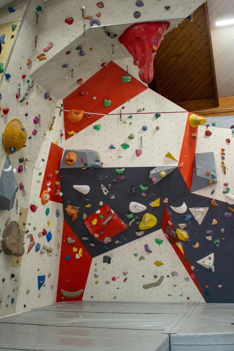 Lead wall in red, grey and white panels with volumes and coloured holds above grey mats