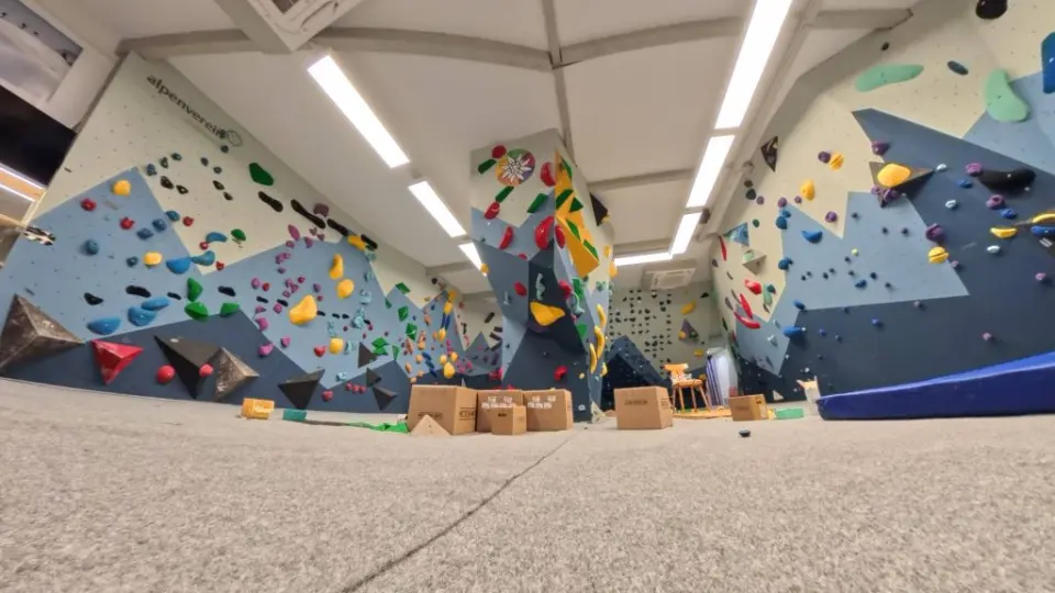 Low view of the rebuilt bouldering hall with blue and white walls around a central pillar