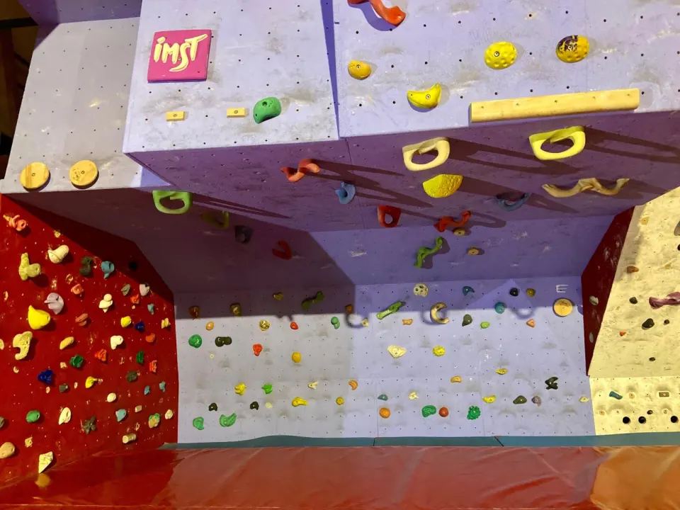 Purple overhang with large jugs and wooden holds beside a red wall