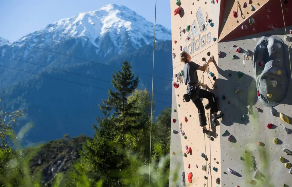 Climber leading up the outdoor wall with a snow-capped peak behind