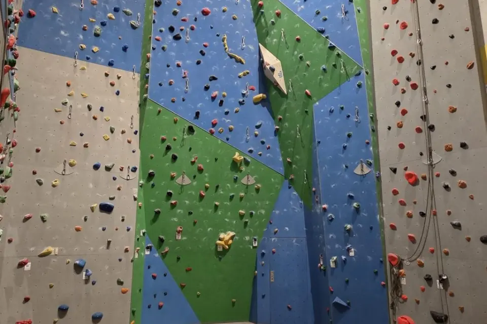 Blue, green and grey lead walls with quickdraws and coloured holds