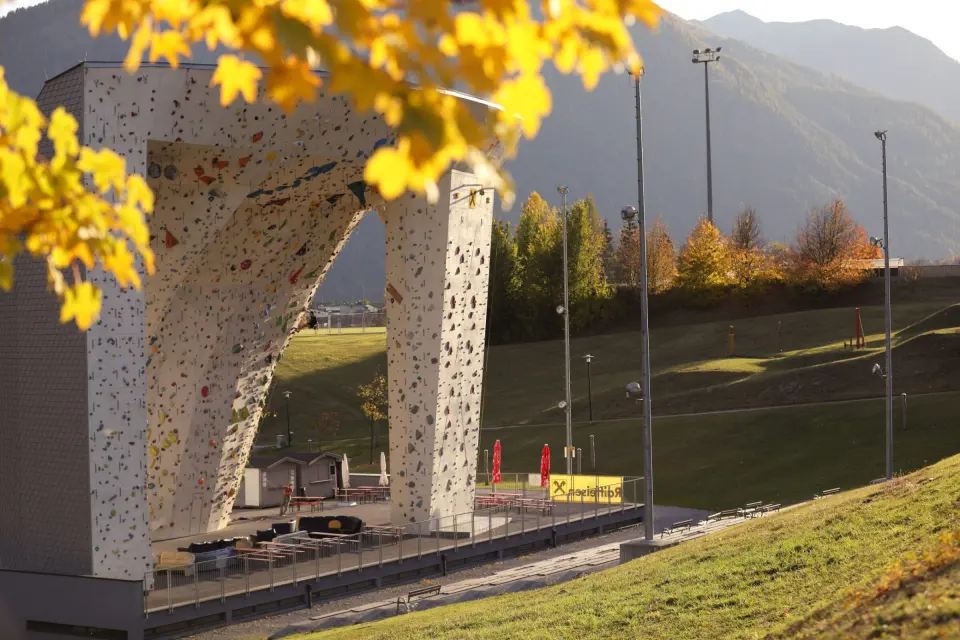 Kletterzentrum Imst's outdoor climbing walls in autumn sun, with mountains behind