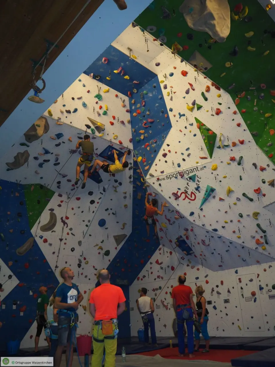 Climbers on roped routes up the overhanging section, with belayers below