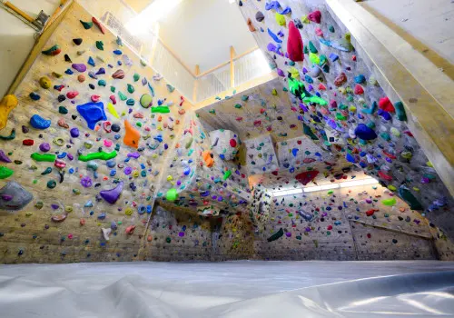 Two-storey bouldering room with colourful holds, overhangs and a padded floor