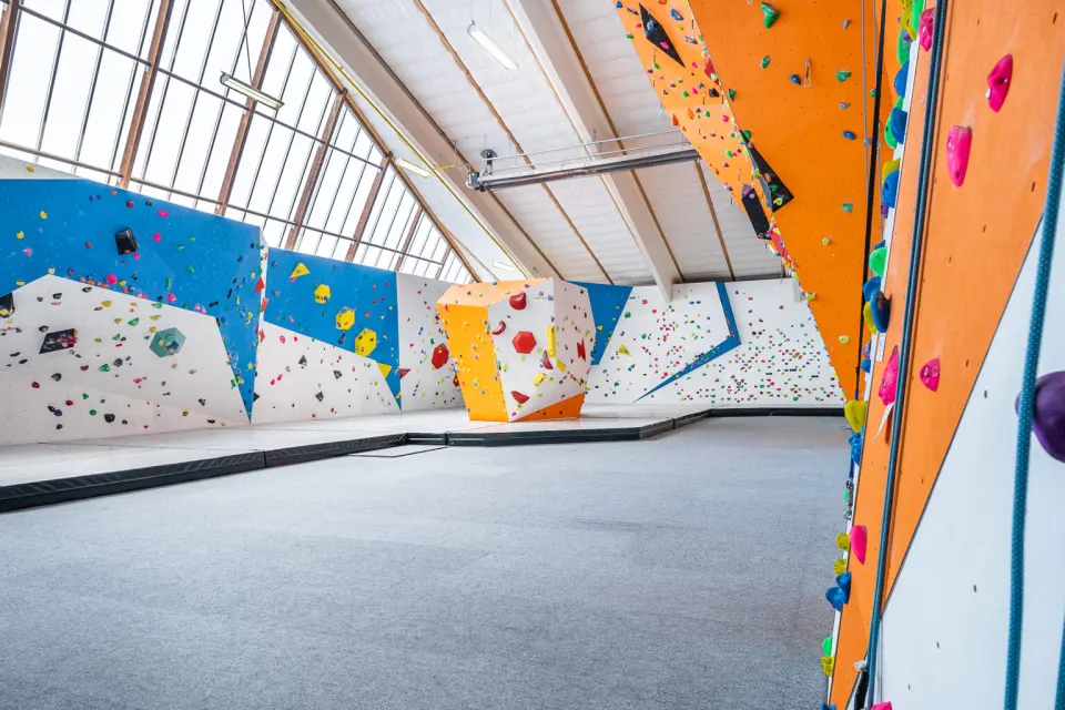 Bouldering area under a glazed roof, with a freestanding block and the orange roped wall