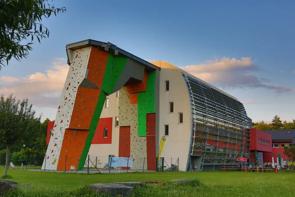 Kletterzentrum Weinburg's outdoor climbing wall and tower beside the hall under a blue evening sky