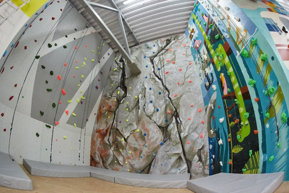 Rope corner with top ropes on a grey wall, a rock-textured wall and a painted wall