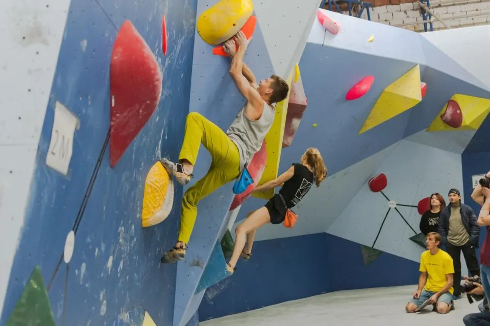 Two climbers on a steep blue bouldering wall during a competition