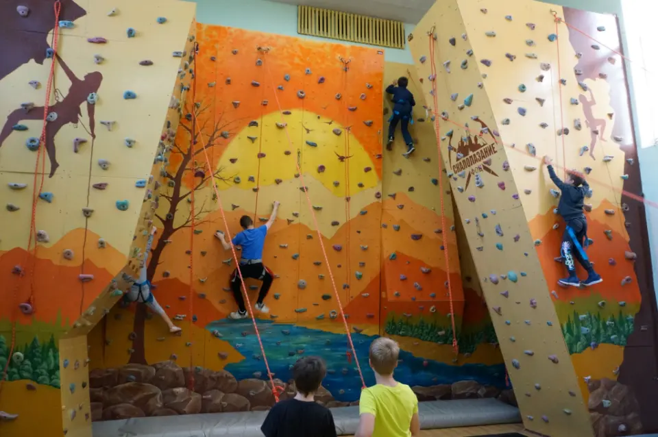 Climbers on top ropes across the sunset-mural climbing wall