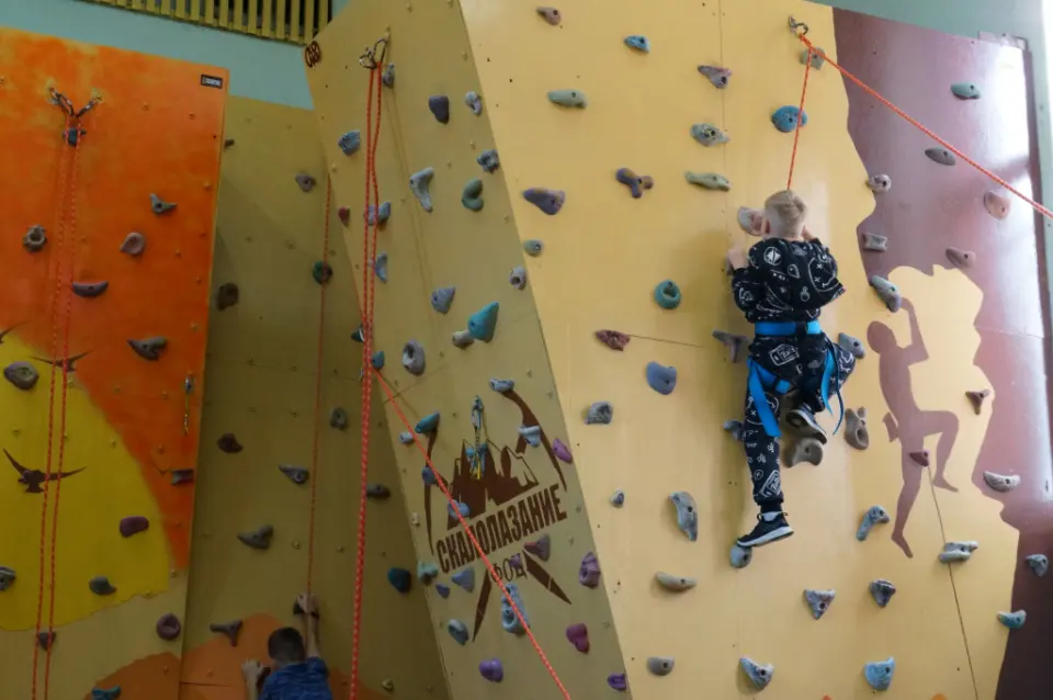 Young climber on an angled panel beside the centre's climbing logo