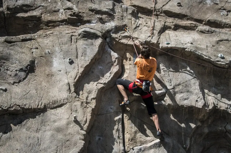 Climber clipping a quickdraw on the carved concrete wall