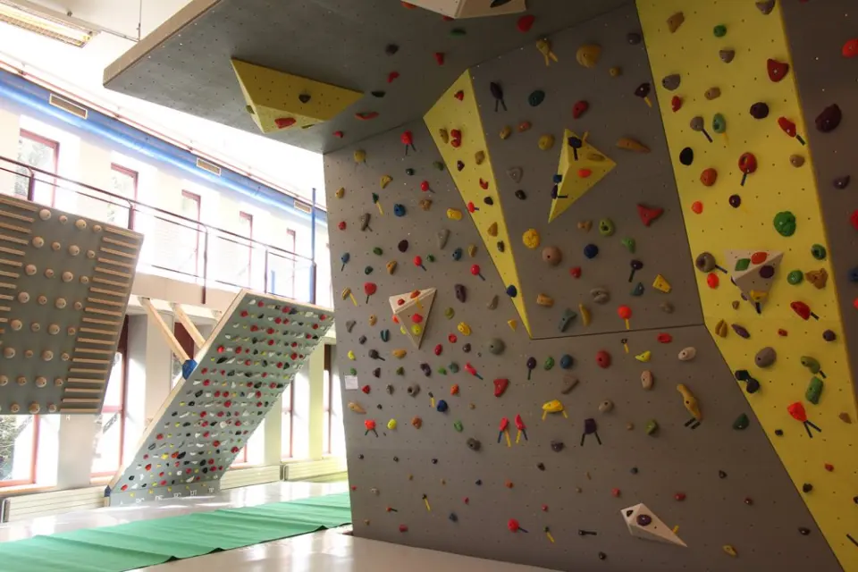 Overhanging bouldering walls with yellow panels beside a campus board and a steep training board