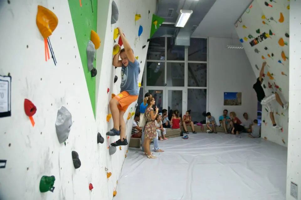 The bouldering room, with climbers on the walls and people resting on the padded floor