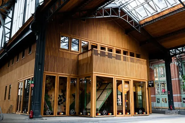 Timber gym pavilion under the iron-and-glass roof of the Gare Maritime