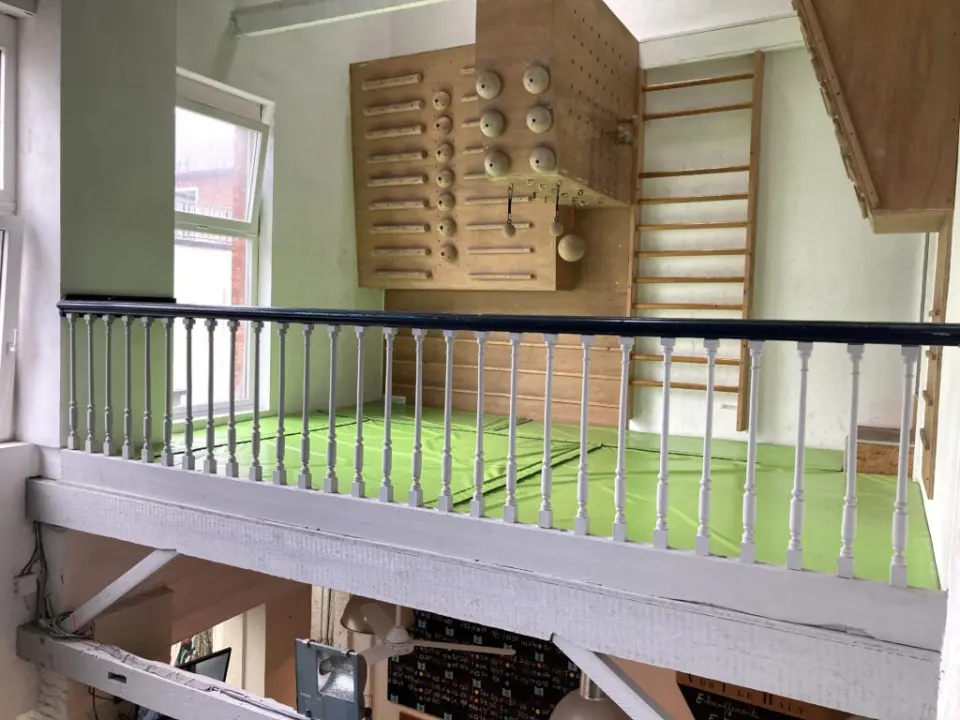 Training mezzanine with a campus board, pinch blocks and wall bars above green mats