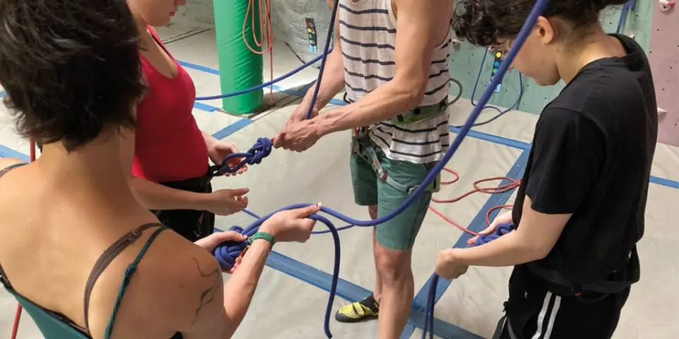 Beginners learning to tie in with figure-of-eight knots on blue ropes