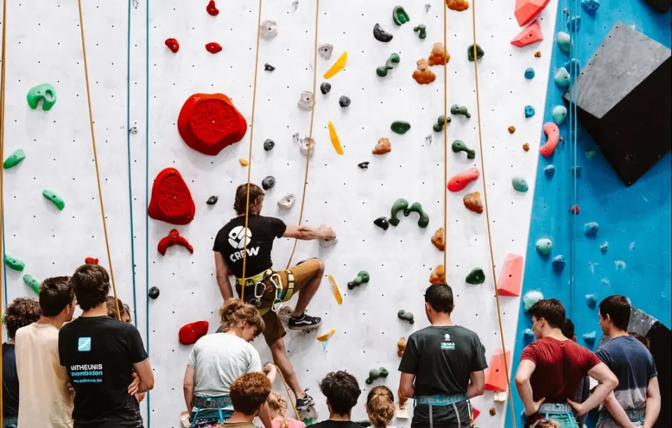 Instructor top-roping on the rope wall while a beginners' group watches