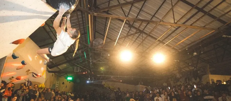 Competitor on a large volume during a competition, watched by a packed crowd