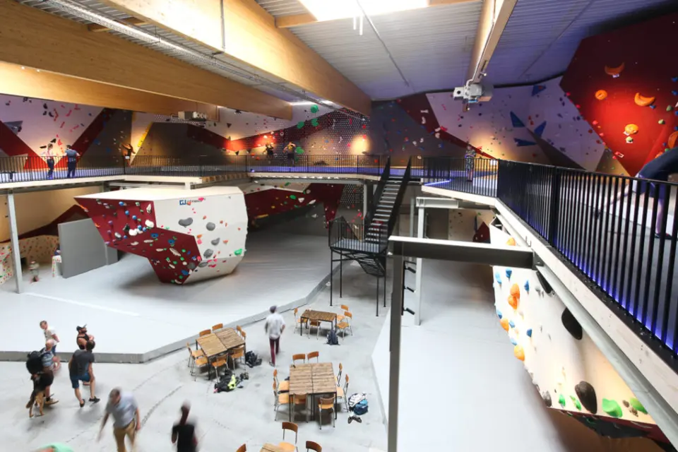 The hall seen from the stairs: a central boulder, café tables below and walls along the upper gallery