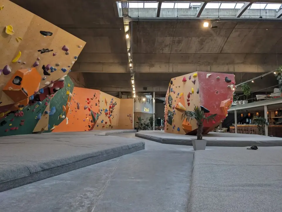 Bouldering walls and a freestanding boulder at The Island in Antwerp, with the bar beyond