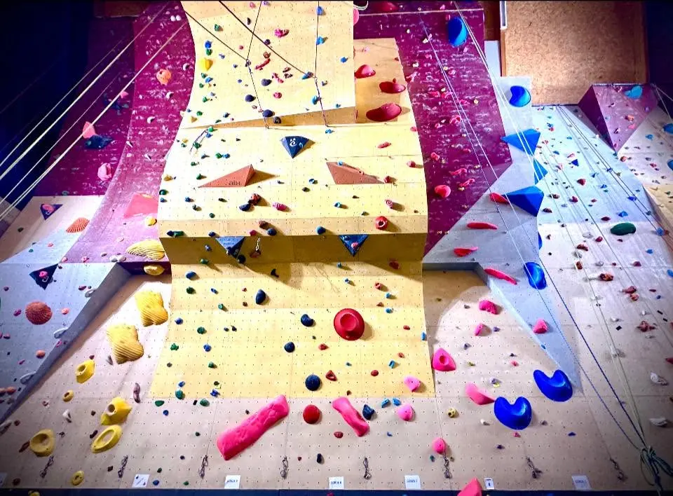 Roped walls with a curved yellow buttress, colourful holds and volumes