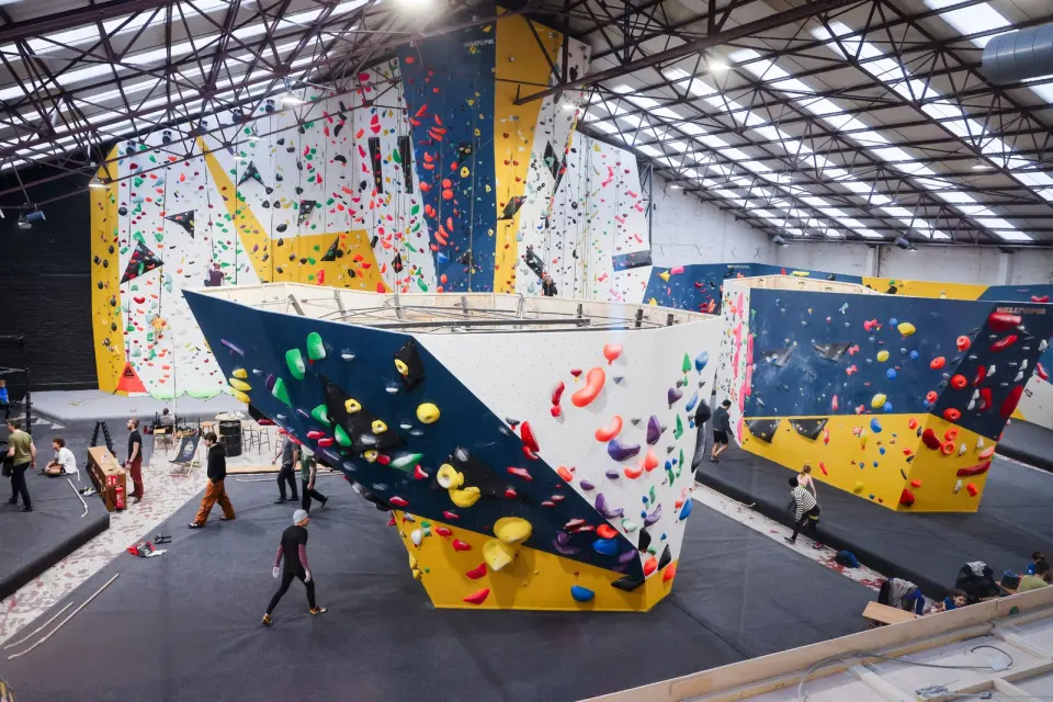 The hall from above, with a freestanding boulder in front of the tall rope walls under a steel roof