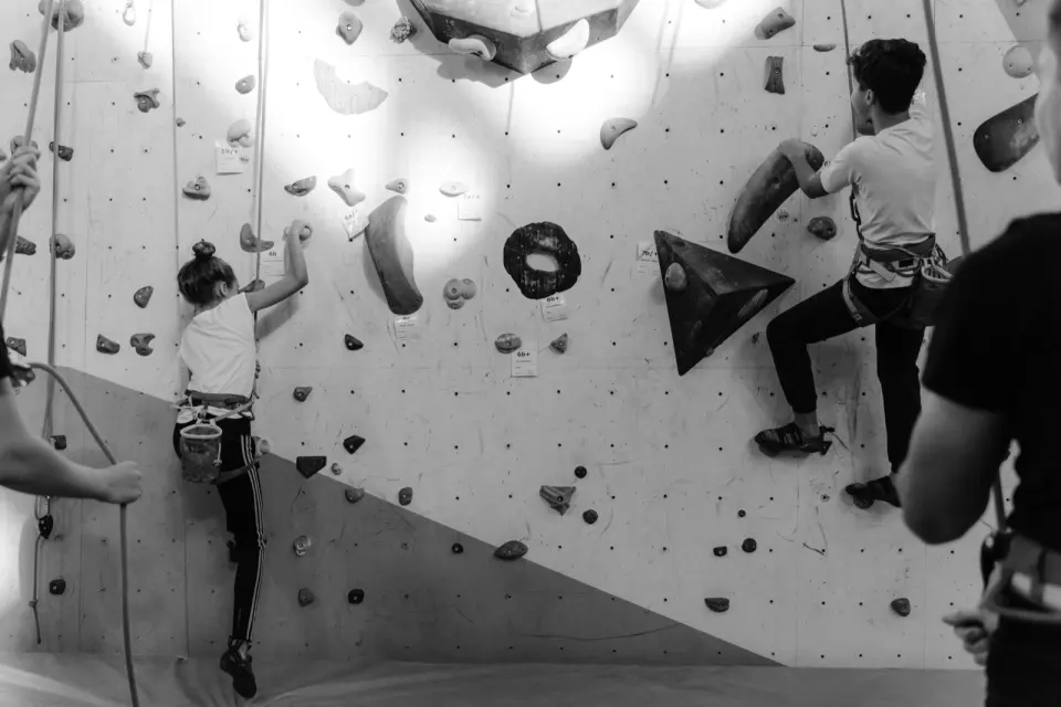 Black-and-white shot of two young climbers on top ropes on the graded rope wall